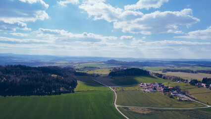Fototapeta premium Green field, farmland with picturesque European landscape. Road in the middle of fields. Soft light. footage video drone view. in the background a range of mountains