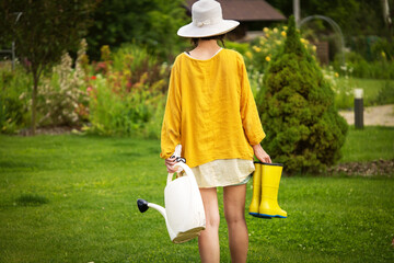 A woman with a watering can is irrigating flowers. © Zhanna