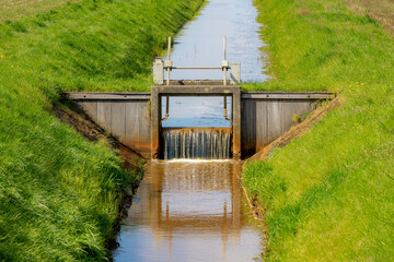 Irrigation concept, A small canal or ditch with little dam or water barrier for agriculture, Farmland in countryside of Holland with green grass meadow, Dutch water management system, Netherlands. - obrazy, fototapety, plakaty