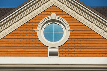 Round window in a red brick wall on facade of a modern house. Architecture details of a modern...