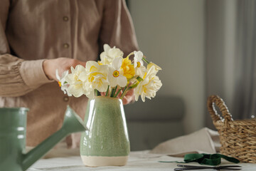 Woman puts a bouquet of fresh flowers into a vase. Decoration and creation of comfort in the house...