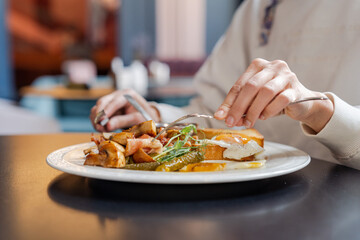 Woman eating delicious breakfast close up. Having breakfast with fried eggs, bacon and vegetables