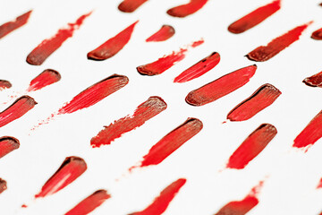 Smears of red cosmetic lipstick on a light background.