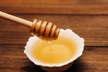 Fototapeta na wymiar Liquid fresh linden honey in a plate with a wooden honey spoon.