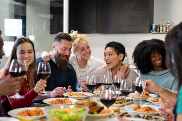 Young friends at the table while eating typical Italian food and spaghetti, meeting to celebrate an event and to be in company, concept of friendship and affective family