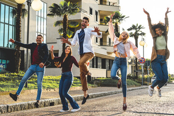 Group of young people jumping and laughing in a city street, happy students celebrating the...