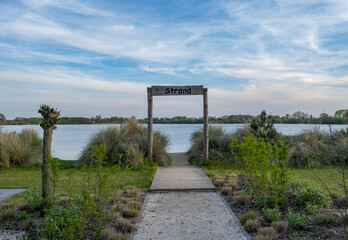 Wooden walkway leading to the lake with blue sky and white clouds Netherlands 