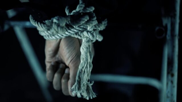 Pan close up shot of hands of a hostage tied to a chair, Hd footage with cinematic dramatic light.