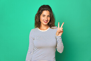 Young caucasian woman isolated joyful and carefree showing a peace symbol with fingers.