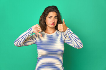 Young caucasian woman isolated showing thumbs up and thumbs down, difficult choose concept