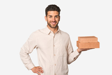 Young man holding a takeaway boxes isolated showing a copy space on a palm and holding another hand...