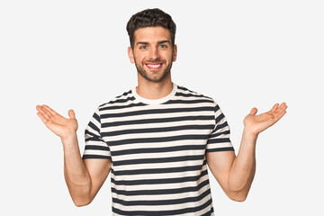 Fototapeta premium Young handsome man isolated makes scale with arms, feels happy and confident.