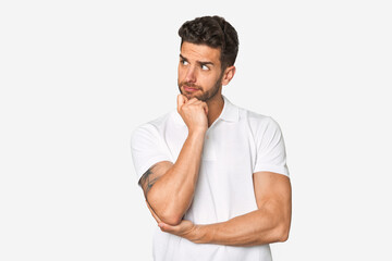 Young handsome man isolated thinking and looking up, being reflective, contemplating, having a fantasy.