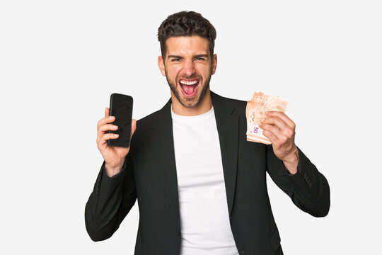 Young businessman seizing his phone and euros, symbolizing lucrative online earnings and financial achievement.