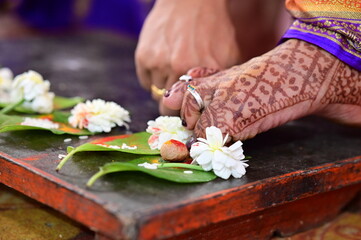 Obraz na płótnie Canvas Toes of indian bride in Saptapadi Ceremony. Floowers, betel nut and leaf. Green and red. Hindu wedding rituals. Maharashtra Hindu Wedding Ceremony. 