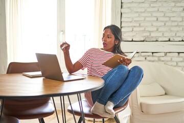 Focused Indian student working on laptop at home.