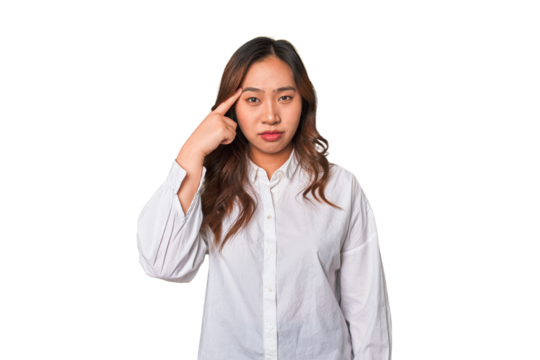 A young chinese woman pointing temple with finger, thinking, focused on a task.
