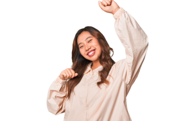 A young chinese woman celebrating a special day, jumps and raise arms with energy.