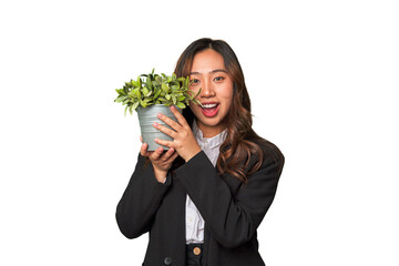 A powerful Chinese businesswoman holds a thriving plant, symbolizing her commitment to sustainable...