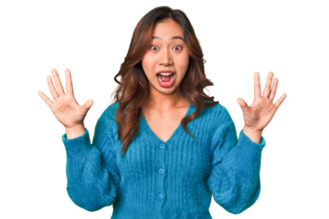 A young chinese woman receiving a pleasant surprise, excited and raising hands.