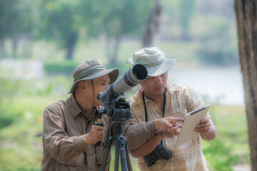 Two Retired Male Friends On Walking Holiday Looking Through Binoculars