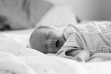 A cramping newborn baby who has just had breastmilk from her mother, with milk stains around her mouth.