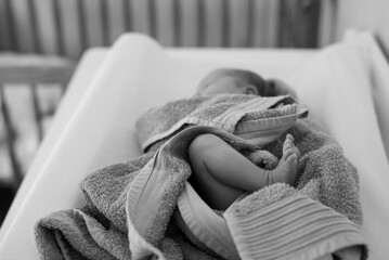 A peaceful and calm baby wrapped up in a towel after bath time to dry her off before getting...