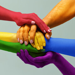 Closeup hands painted in different colors as rainbow flag holding together symbolizing tolerance unity love, LGBT on light background. Freedom of choice - obrazy, fototapety, plakaty