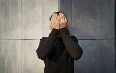 Concept of societal blindness, as a young man covers his eyes with his hands. Comunity can often turn a blind eye to important issues that affect our world