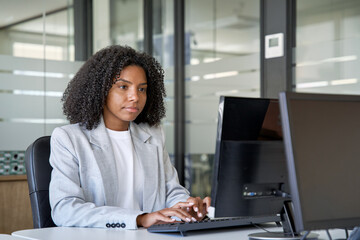 Middle age business woman working, browsing, and typing on touchscreen pc laptop. African American...