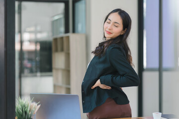 A businesswoman stretches lazily on her desk for relaxation while working in the office.