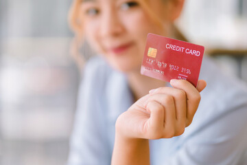 Cropped shot of asian young woman bank client customer showing mockup red credit card for online e-commerce transactions, cashback, loan, payment, debt shopping.