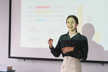 Fototapeta premium The female Chief Analyst is conducting a meeting presentation for a team of economists. The projector screen shows graphs, product sales, revenue growth strategies, and e-commerce analysis.
