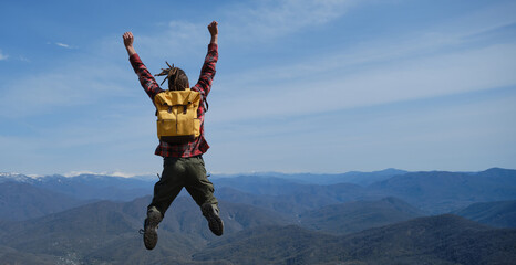 Healthy active lifestyle. Young guy with dreadlocks went hiking in mountains. Man with yellow...