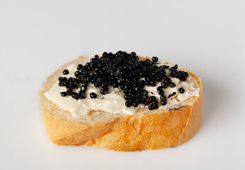 white bread with butter and black caviar on a white background