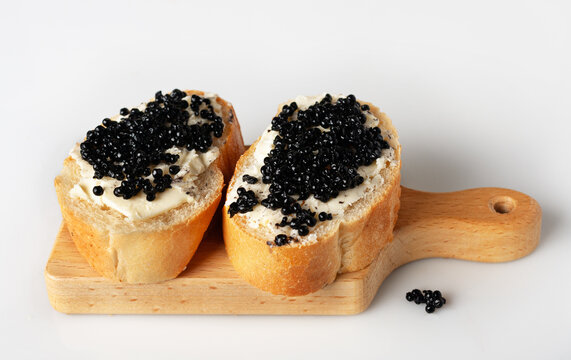 two sandwiches with butter and halibut caviar on a wooden board