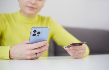 Young woman paying online with a credit card and smart phone. Unrecognizable female person making a purchase in mobile app
