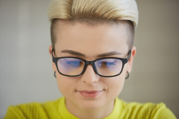 Portrait of a beautiful tom boy female working on a computer. Stylish white woman in classic glasses studying online