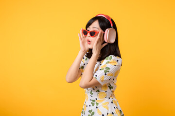 Smile pretty asian model person listen music song and enjoy dance with wireless headphone online audio radio sound. Positive fun exited joyful youth female woman on yellow isolated background studio
