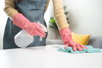 happy Female housekeeper service worker wiping table surface by cleaner product to clean dust.