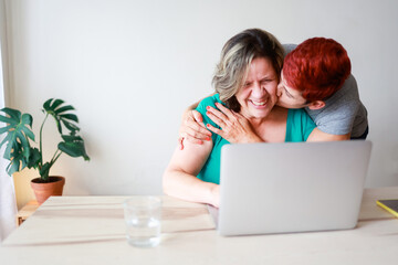 Senior gay family - Lesbian couple having fun using computer laptop inside home - LGBTQ love concept - Focus on left female hands