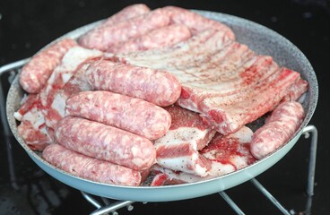 raw sausages and pork ribs ready to be grilled on the alfresco barbecue