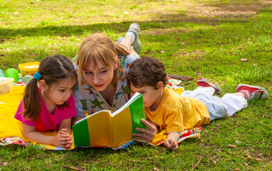 Joyful family in the park on the grass reading a book