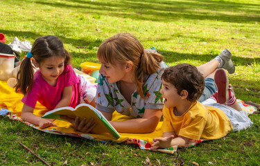 Joyful family in the park on the grass reading a book