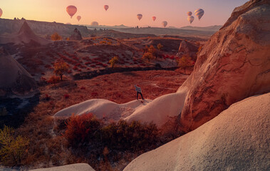 Tourist man in Goreme national park with over deep canyons, valleys sunset Cappadocia sunset with hot air balloons. Aerial top view place of Turkey
