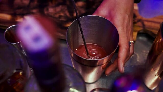 The female bartender stirs the cocktail in a silver cup with a practiced hand, mixing the flavors to perfection. She adds a final touch of garnish, creating a visually appealing and Generative AI