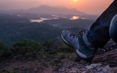 Hiker on the mountain with trekking boots, beautiful sunset view with hiking boots