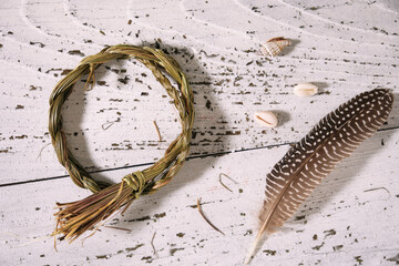 Sweetgrass braid (Hierochloe odorata), also called vanilla grass, and incense feather on old white...