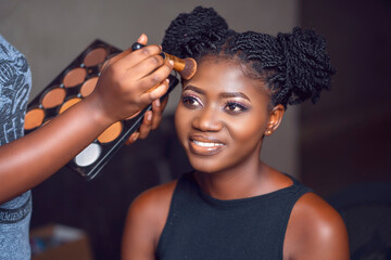 close up image of beautiful african lady applying a facial product- black woman applying make up-...