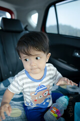 Malay boy drink water and pose in the car while travelling.